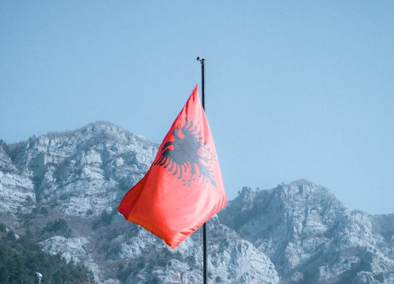 rocky mountains and an albanian flag in foreground